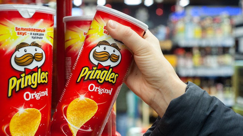 hand reaching for pringles in grocery store
