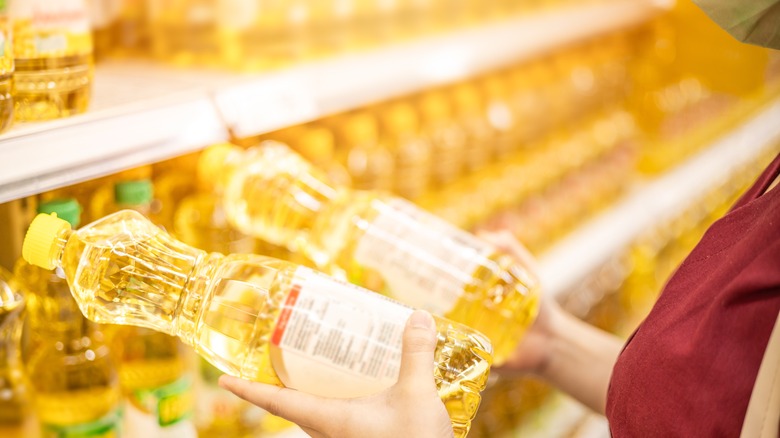 person holding cooking oil bottles