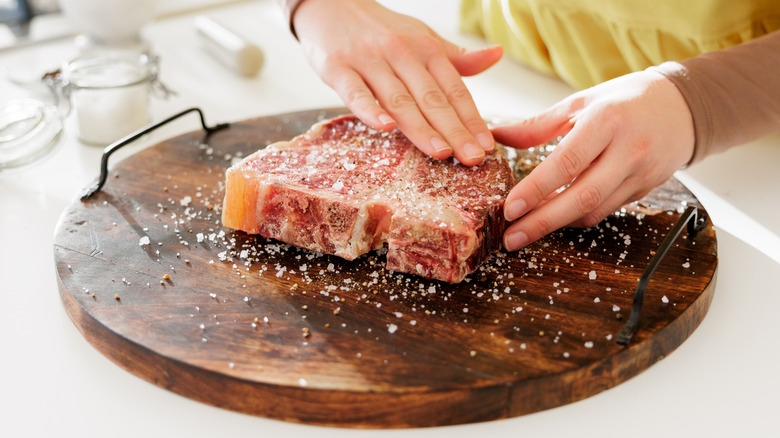 Rubbing seasoning onto raw steak