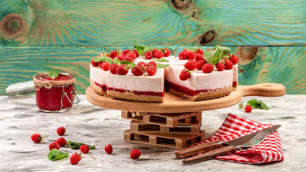 raspberry cheesecake sitting on a table with a fork and knife