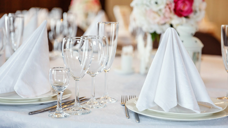 white napkins folded into pyramids on plates, set of drinking glasses