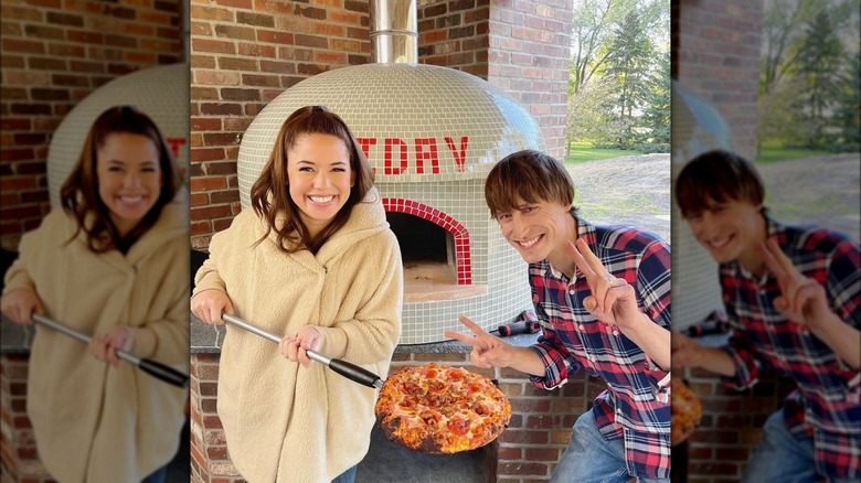 Yeh with pizza in front of a domed, tiled pizza oven