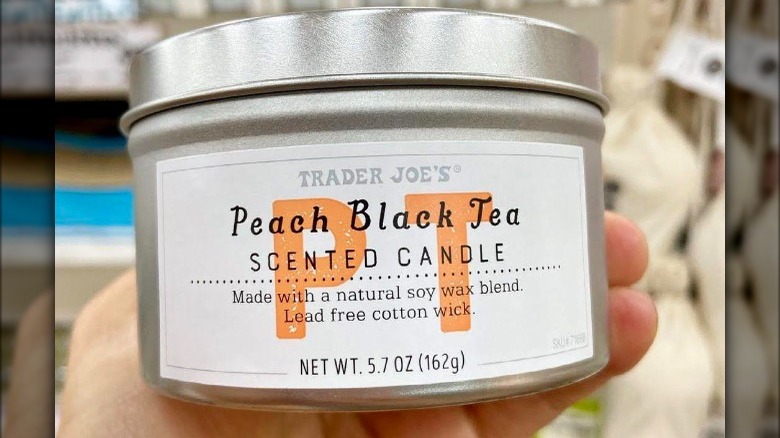 Person holding a Peach Black Tea candle from Trader Joe's