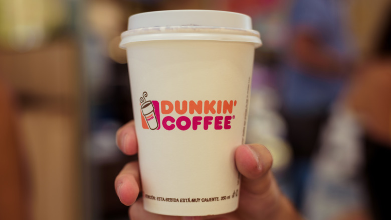 Person holding a cup of coffee from Dunkin'.