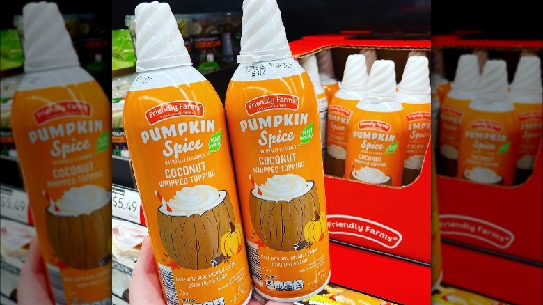 Person holding two cans of Pumpkin Spice Coconut Whipped Cream from Aldi