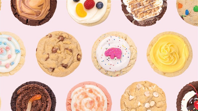 An assortment of Crumbl Cookies on a pink background.