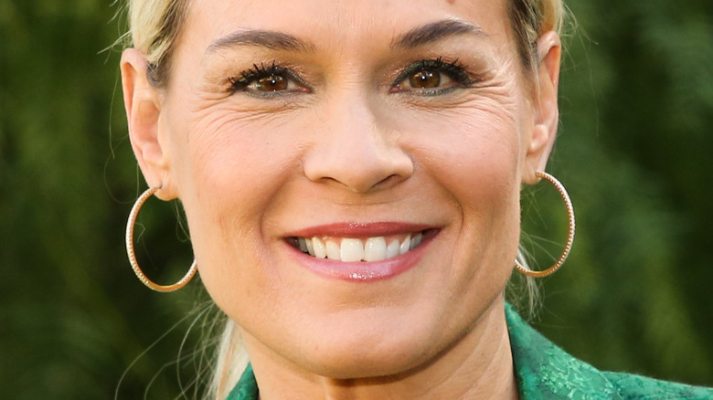 Cat Cora smiling in green blazer and hoop earrings