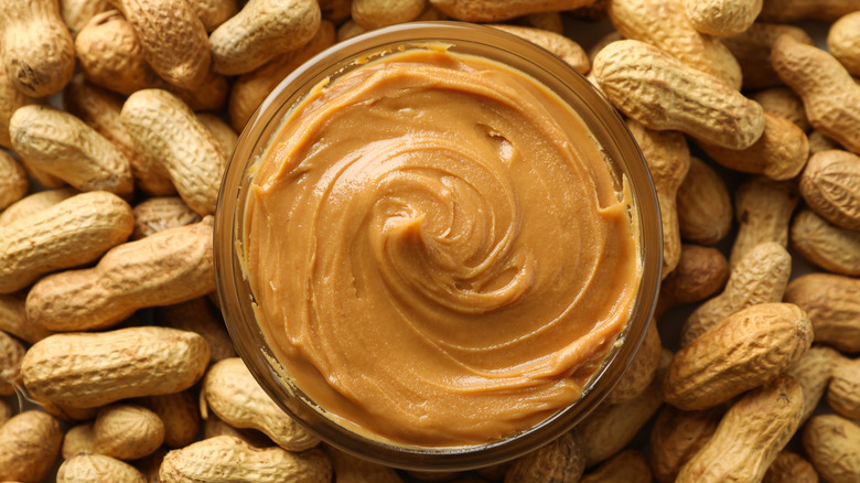 jar of peanut butter surrounded by peanuts