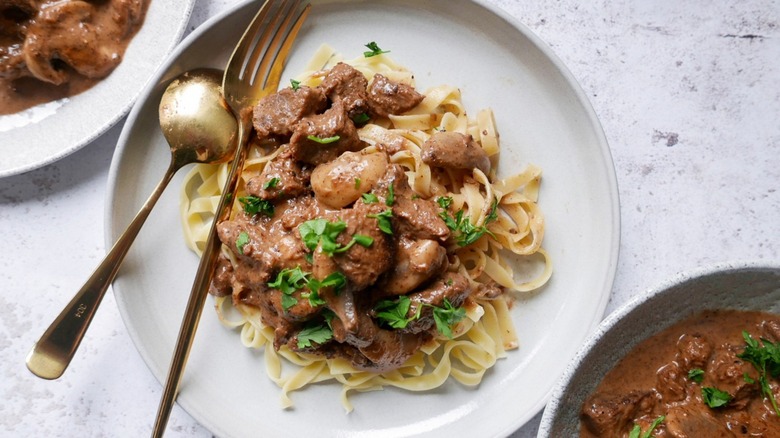 Three plates filled with beef stroganoff.