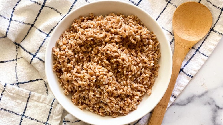 Cooked farro in a bowl with a wooden spoon