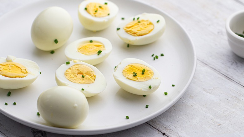 Hard-boiled eggs, cut and whole, on plate with chives