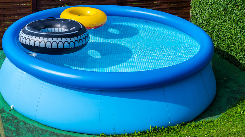 Blue kiddie pool filled with water and donut shaped floaties