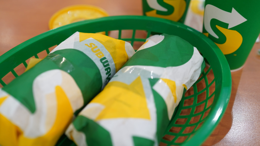 Green basket with wrapped Subway sandwiches