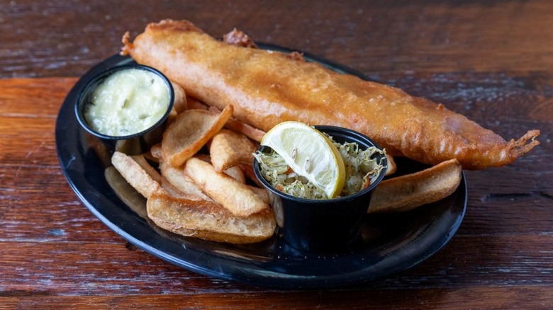 Fish and chips on plate atop wooden table