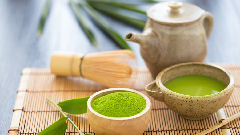 Two bowls of matcha with bamboo whisk and teapot