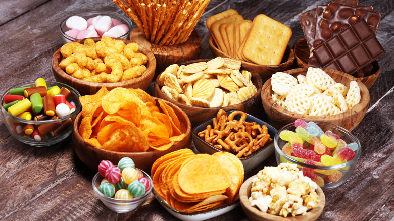 Unhealthy snacks in bowls on wooden table