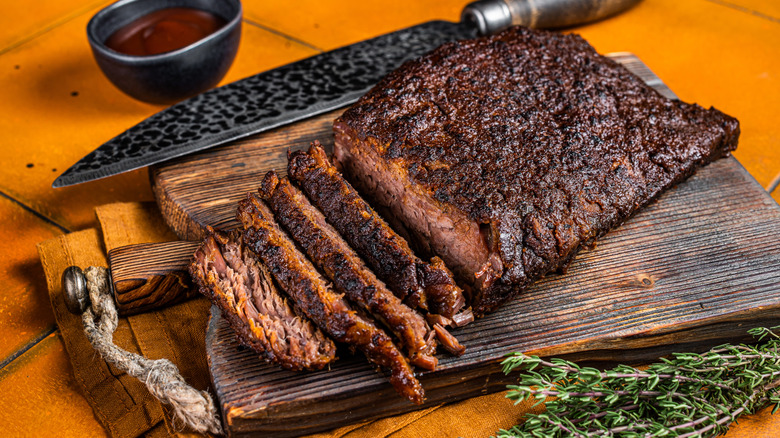 Smoked brisket on cutting board with knife