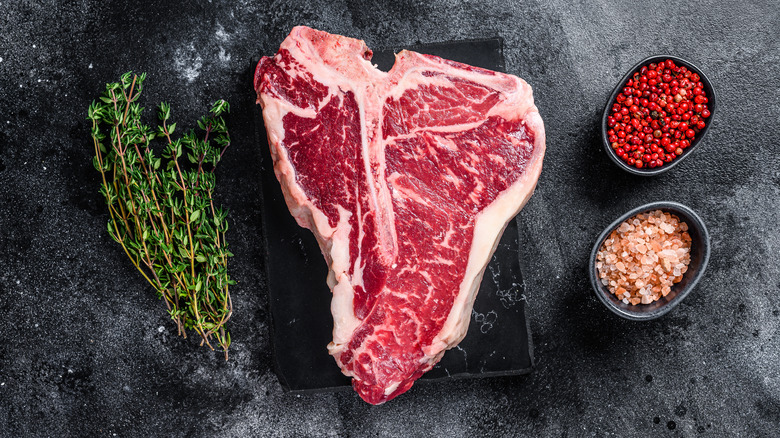 T-bone steak next to herbs and seasonings