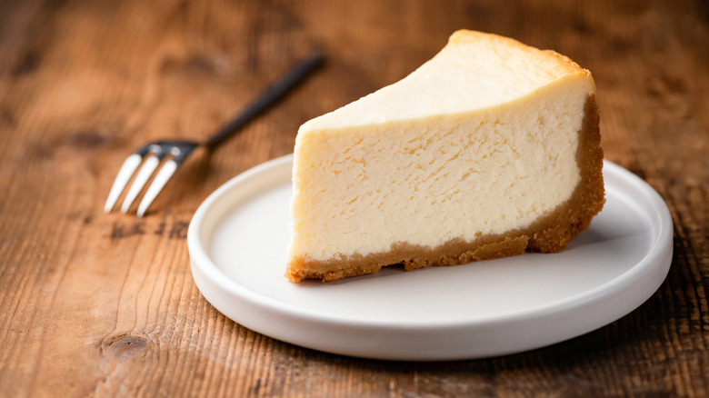 Cheesecake slice on white plate with fork