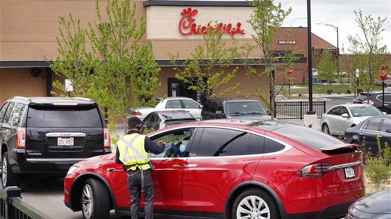 A Chick-fil-A employee taking an order at a drive thru