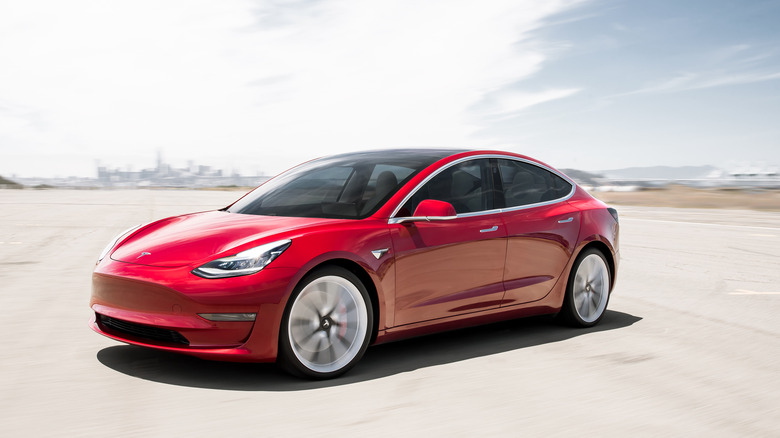 Red Tesla car against sky background