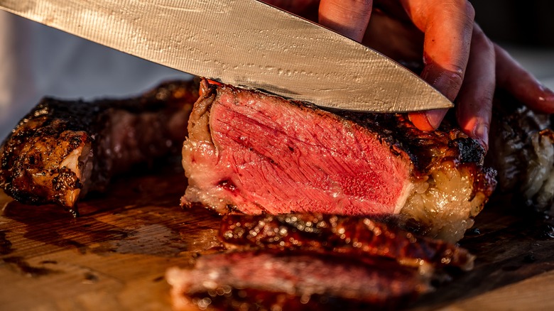 chef's knife cutting into steak with pink center