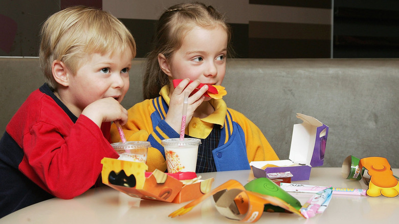 two kids eating McDonald's Happy Meals at table