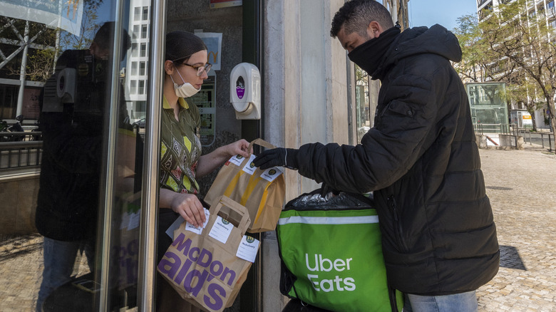 Uber eats delivery man delivers McDonald's food to woman in apartment entrance