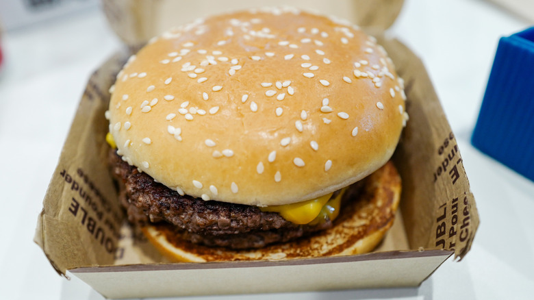 closeup of a McDonald's burger with sesame seed bun in takeout box