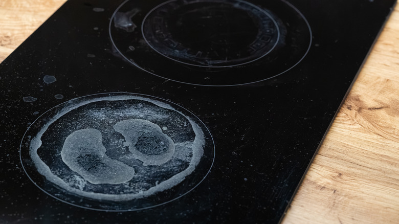 Black ceramic stovetop with stains on it.