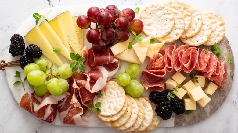 A charcuterie board with cheeses, meats, fruits, and crackers