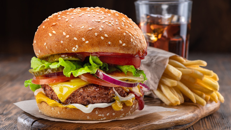 A hamburger served with fries and a soft drink.