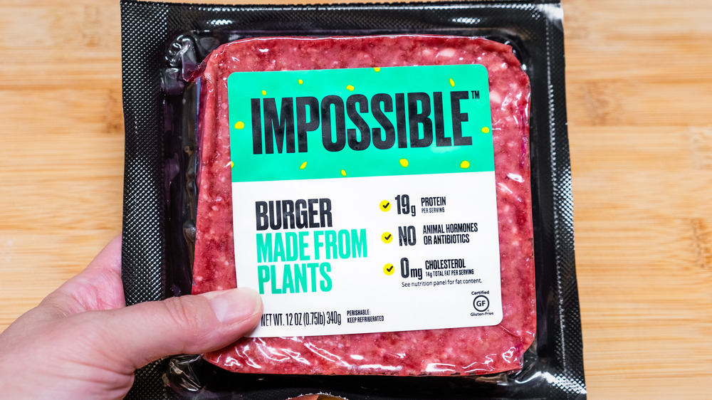 Hand holding a package of Impossible burger meat