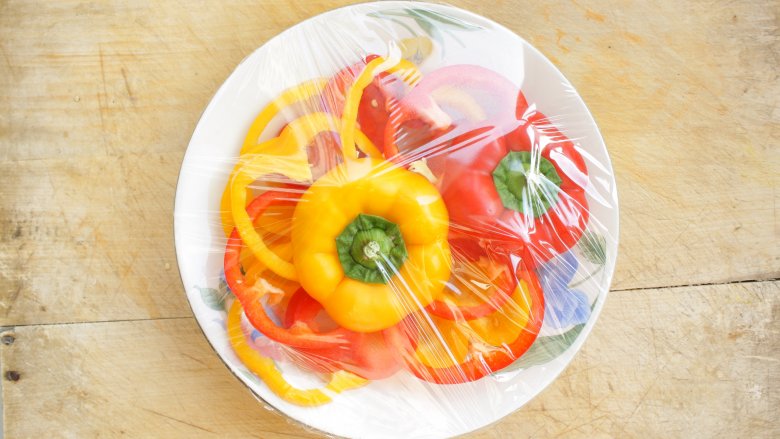 Bell peppers on plate with plastic wrap