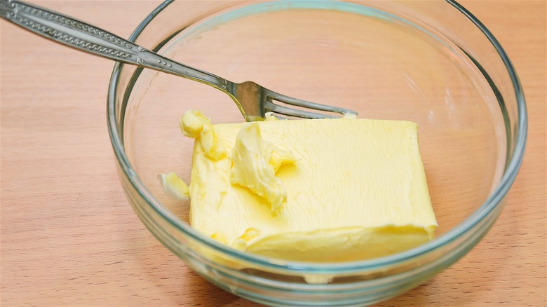 Softened butter in a glass bowl with a fork.