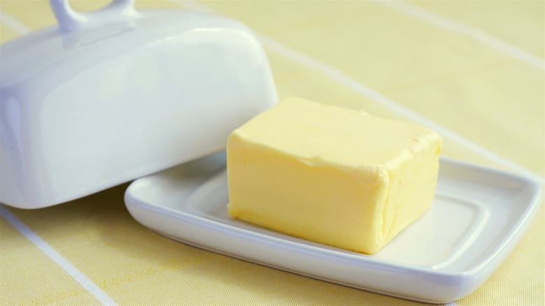 A room-temperature block of butter in an open ceramic butter dish.