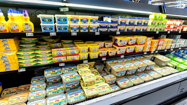 Multiple popular margarine brands on display in a supermarket chiller.