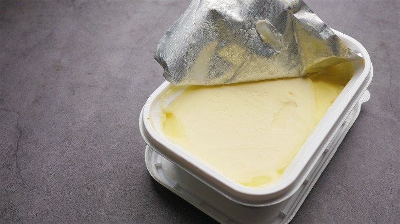 An open container of margarine on a gray table.