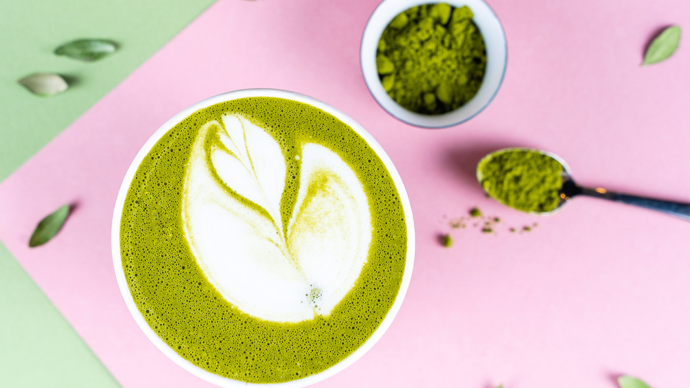 Matcha powder next to a matcha latte 