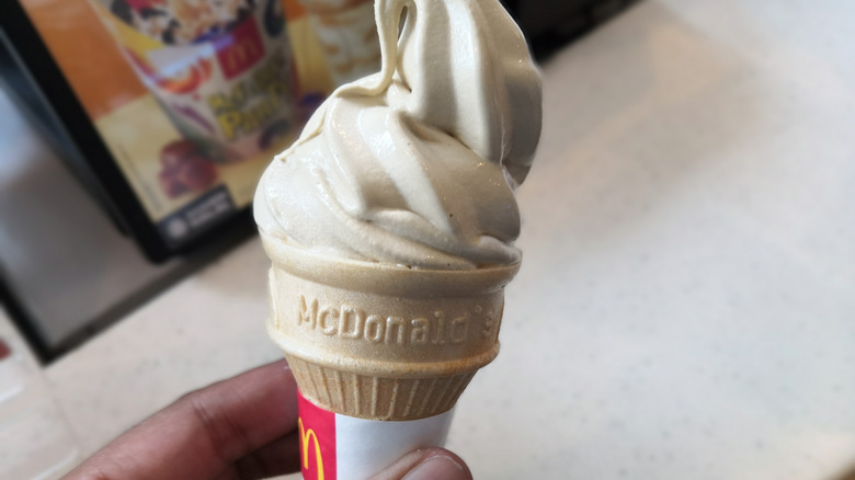 Person holding vanilla soft serve cone close up