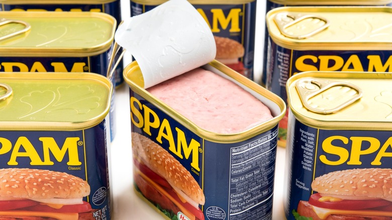 Several cans of Spam, with one lid popped open to show the contents.