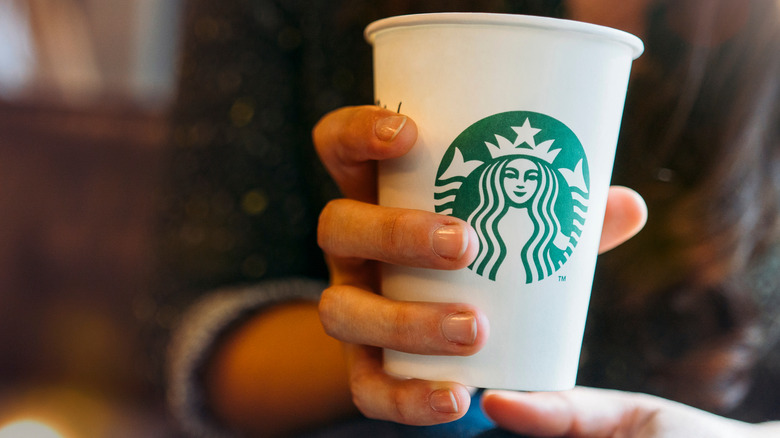 Hand holding white Starbucks cup