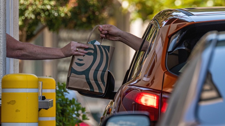 Starbucks worker giving customer drive-thru order