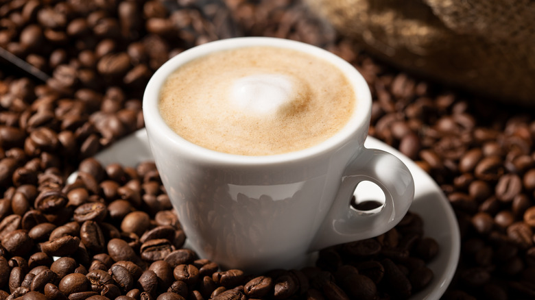 cappuccino surrounded by coffee beans