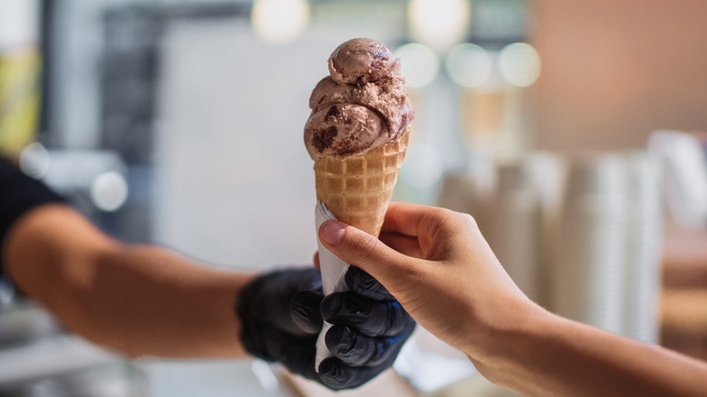 Vendor in black gloves passes ice cream to customer