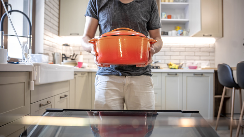man putting dutch oven in oven