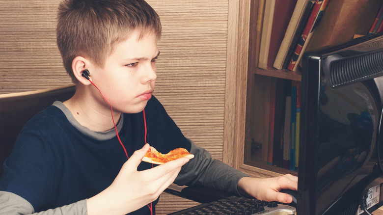 boy at computer eating pizza