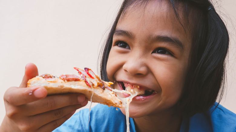 young girl eating pizza