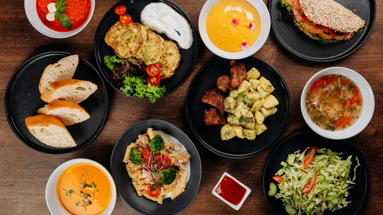 Various soups, salads, pastas, and breads on restaurant table.