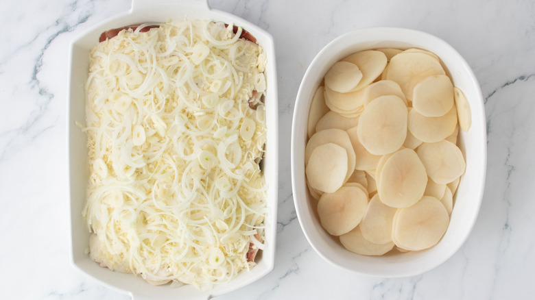 Onion-topped casserole next to bowl of sliced potatoes
